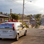 Viatura da brigada militar circulando por uma rua de chão batido do bairro Lomba do Pinheiro