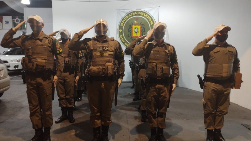 Policiais Militares em forma prestando contin&ecirc;ncia ao terreno.