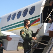 Policias militares do Batalhão de aviação carregando as doses das vacinas para dentro do avião