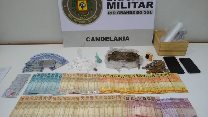 Ao fundo o banner da Brigada Militar. Sobre uma mesa o material apreendido.