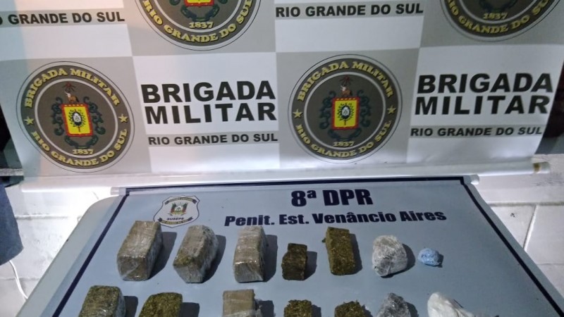 Ao fundo o Banner da Brigada Militar. Sobre uma mesa com o banner da Susepe a droga apreendida.