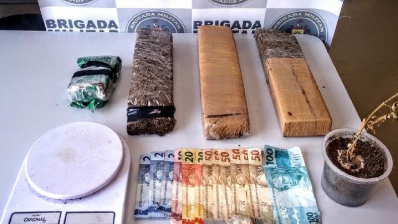 No fundo o Banner da Brigada Militar. Na frente sobre uma mesa os materiais preendidos.