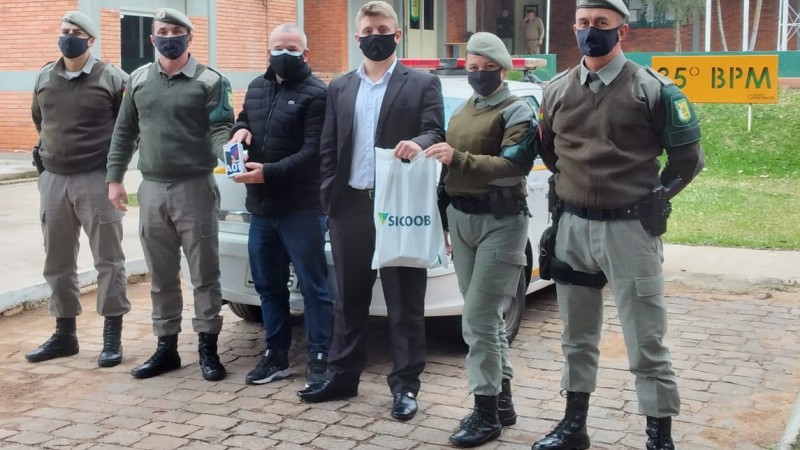 Policiais Militares recebendo a doa&ccedil;&atilde;o de um telefone celular para patrulha maria da penha do munic&iacute;pio de Cachoeira do Sul.