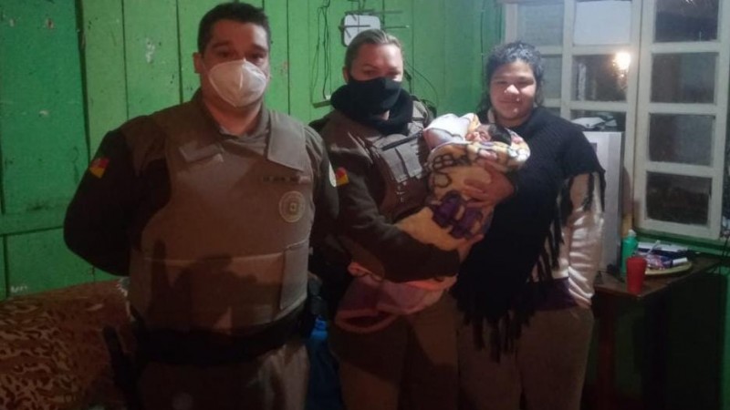 Policiais Militares com o beb&ecirc; salvo em seu colo.