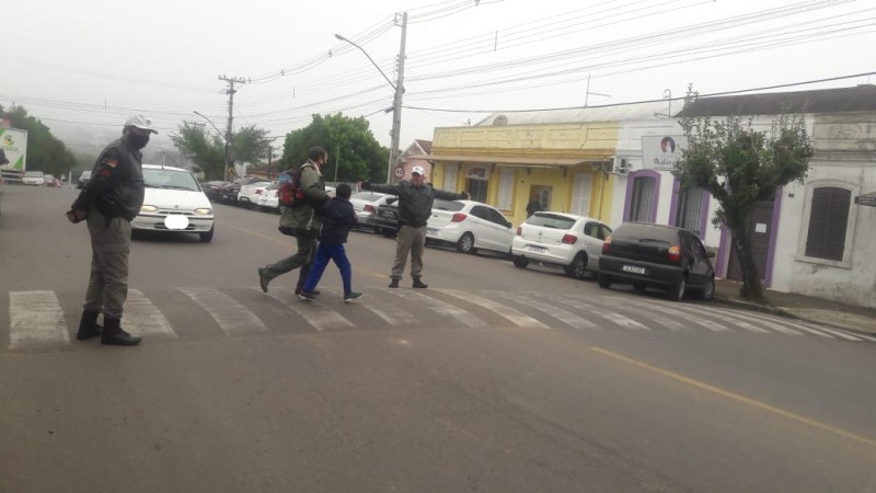 Dois policiais militares parando o tr&acirc;nsito para que pedestres atravessem em seguran&ccedil;a a faixa de seguran&ccedil;a