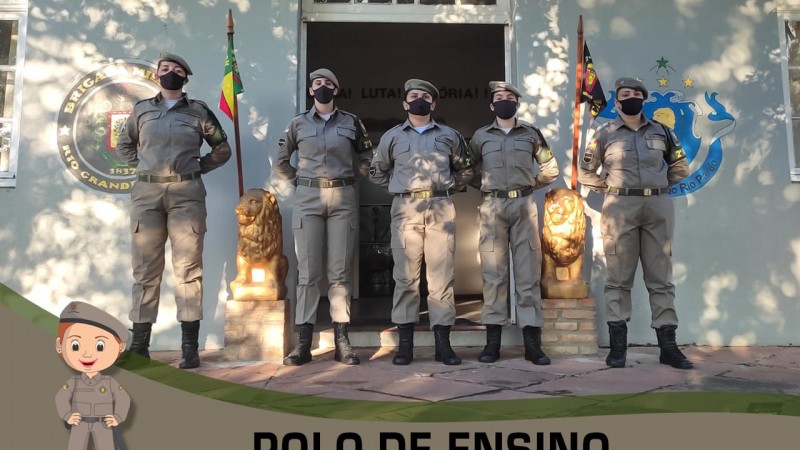 Cinco alunas-soldados perfiladas e ao fundo o quartel da escola de forma&ccedil;&atilde;o.