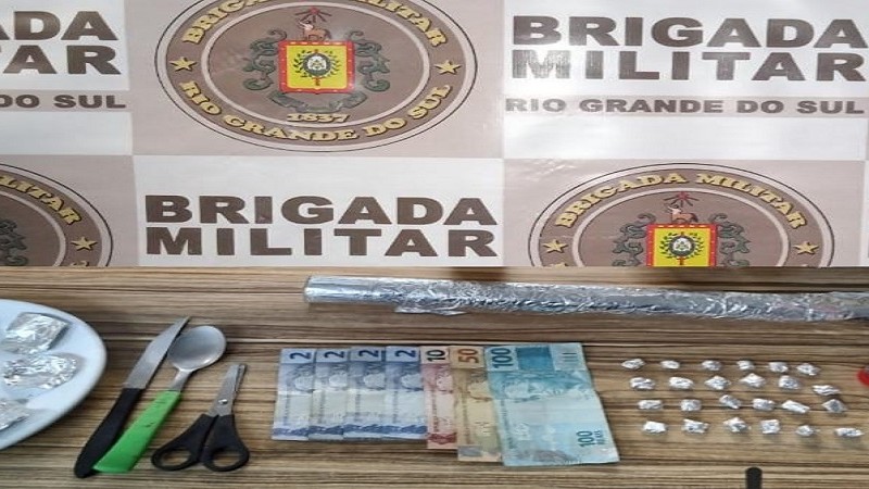 porções de droga, dinheiro, papel laminado, tesoura e outros materiais 