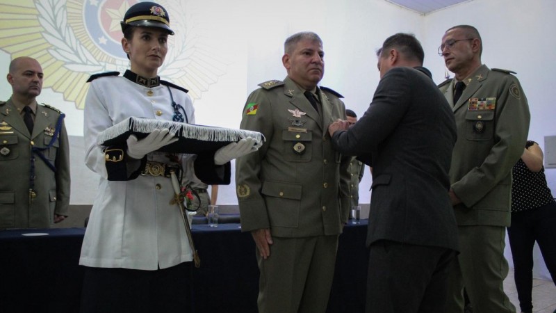 Militares e Secretário de segurançacestão de pé fazendo a entrega de medalha