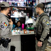 Dois policiais militares em fiscalização em uma loja de celulares.