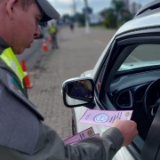 Policial Militar entrega folder explicativo sobre o combate à violência contra a mulher para motoristas no trânsito