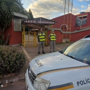 Foto mostra dupla de policiais militares posicionados em frente ao portão de uma escola