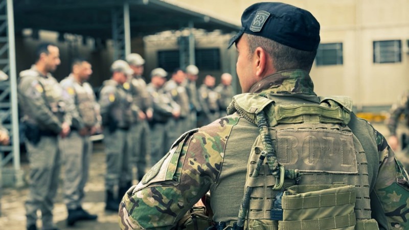 operador do BOPE de costas ao fundo policiais militares recebendo instrução