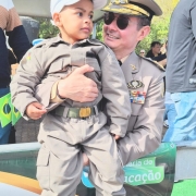 Criança acompanha o desfile com farda da BM