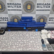 mesa da BM com os materiais apreendidos, tabeletes de maconha, proções de drogas, aparelhos celulares, balanças de precisão, entre outros. 