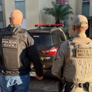 Policial civil e policial militar, ambos de costas e fardados