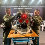 Mecânicos aparecem trabalhando em um equipamento sobre uma mesa