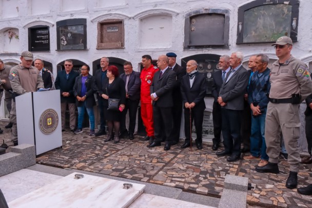 Autoridades em fileira e em torno do jazigo no cemitério.