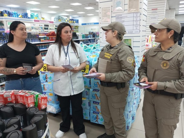 PMs femininas aparecem um uma farmácia conversando com funcionária e cliente.