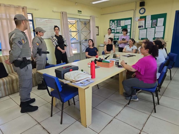 PMs feminas e civis em torno de uma mesa durante uma reunião