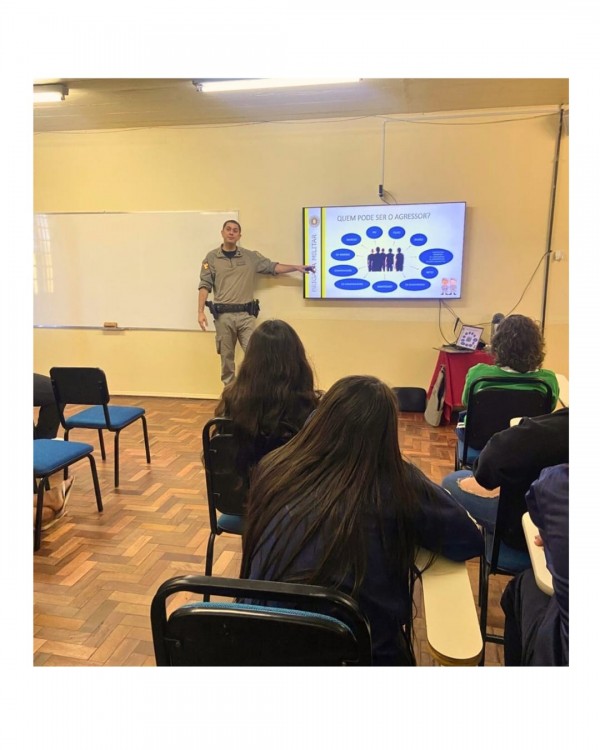PM palestra utilizando slides e aparece um público feminino