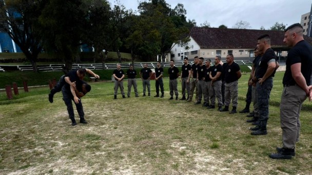 PMs em pé e em círculo assistindo uma técnica de projeção ao solo