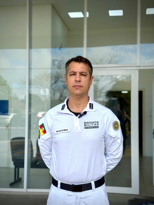 O PM aparece com a farda branca em pé e em frente à sede do Hospital. 