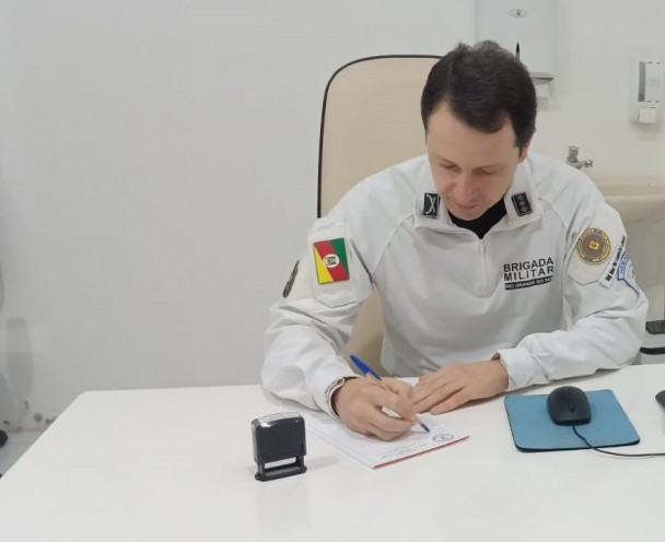 PM apresenta-se fardado e em sua mesa de trabalho no Hospital e preenchendo um receituário. 