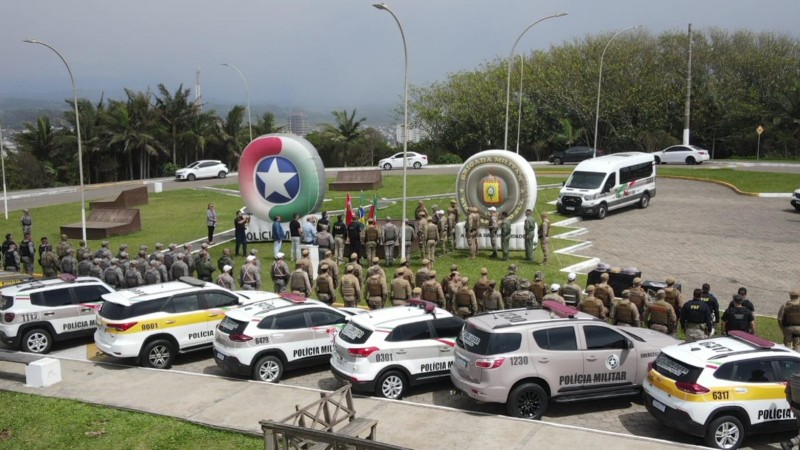 Vista de cima mostra veículos das Polícias, fileiras de policiais, e dois tótens infláveis com os brasões das PMs de Santa Catarina e a Brigada do Rio Grande do Sul.