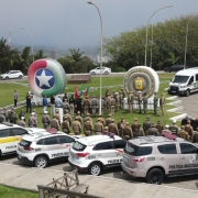 Vista de cima mostra veículos das Polícias, fileiras de policiais, e dois tótens infláveis com os brasões das PMs de Santa Catarina e a Brigada do Rio Grande do Sul.