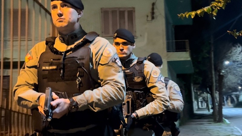 Três PMs aparecem durante a atuação noturna em um bairro de Lajeado, estão fardados com armas em punho e em fila. 