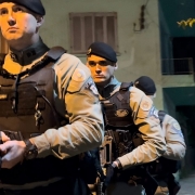 Três PMs aparecem durante a atuação noturna em um bairro de Lajeado, estão fardados com armas em punho e em fila. 