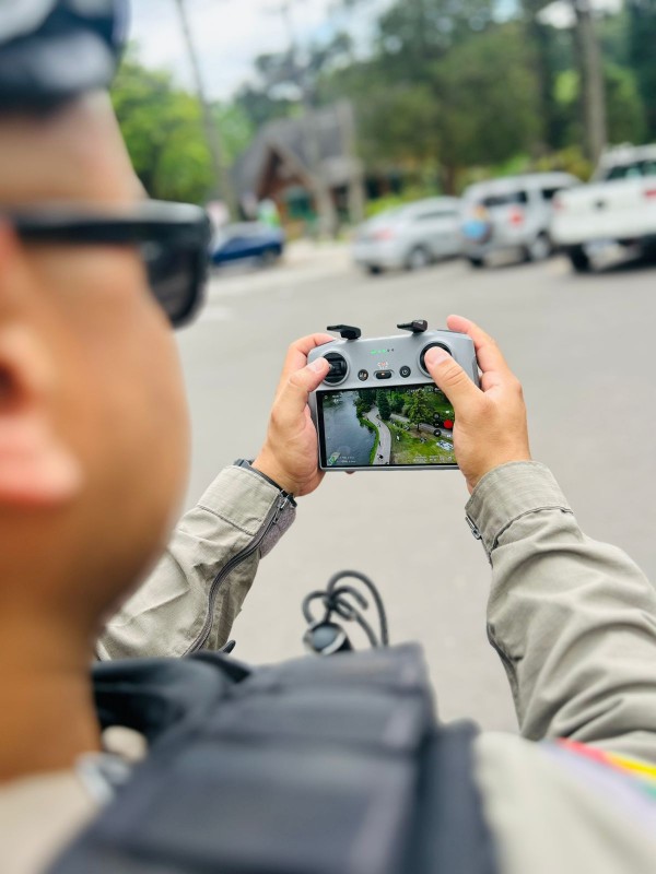 PM pilota o drone e em destaque aparece a imagem aérea na tela do equipamento.  