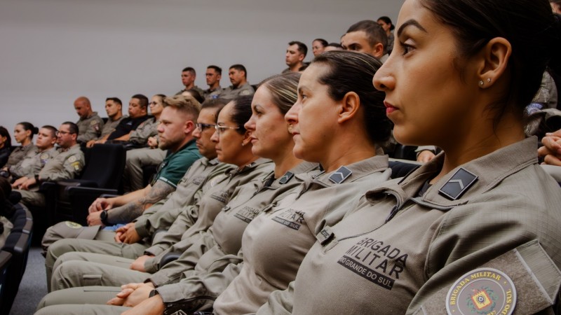 Foco em uma fileira com PMs femininas de lado. Ao fundo vè-se mais fileiras lotadas com PMs.