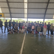 Equipes do Comando de Choque aparecem na fotografia entre os alunos de uma turma do Ensino Fundamental na área do Ginásio de uma Escola. 