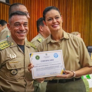 Subcomandante-Geral aparece ao lado de uma aluna que mosrta o certificado recebido.