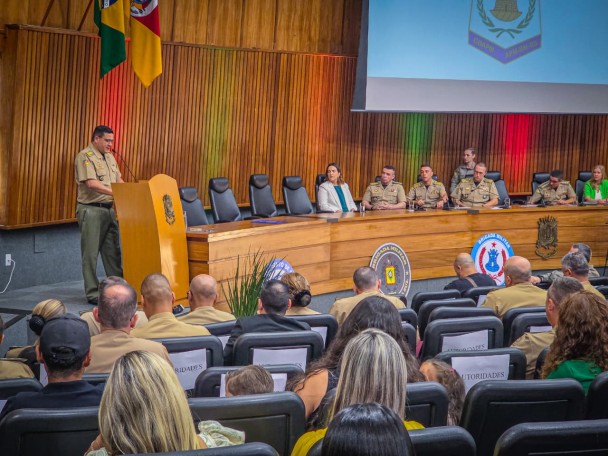 Público do auditório e autoridades da mesa dirigem o olhar para o paraninfo que fala ao púlpito