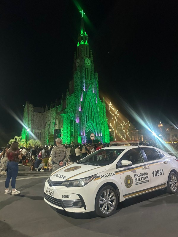 Viatura aparece ao lado de um PM em meio ao público à noite em um dos eventos de Natal 