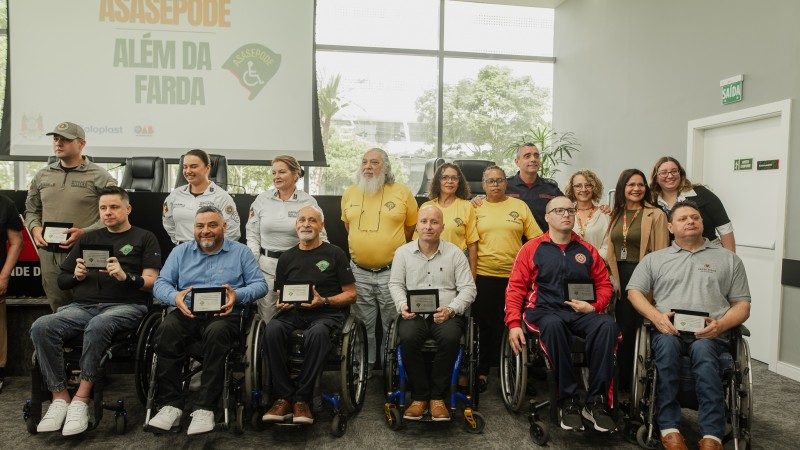 Duas fileiras, sendo uma com as pessoas em p&eacute; e outra com cadeirantes mostrando as placas recebidas por reconhecimento. 