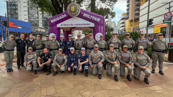 Duas fileiras de PMs e outros policiais em um posto-base da BM montado no canteiro central de uma avenida. 