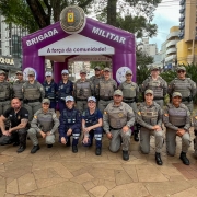 Duas fileiras de PMs e outros policiais em um posto-base da BM montado no canteiro central de uma avenida. 