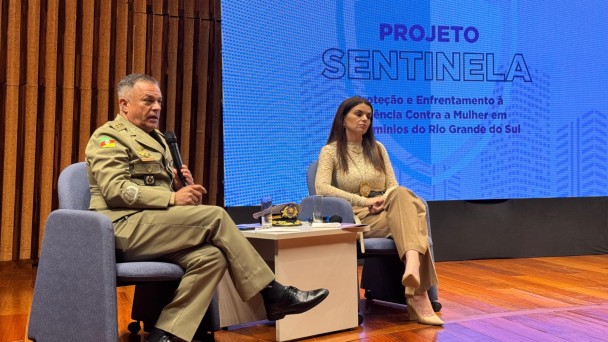 Tenente-coronel PM Moraes sentado no palco durante a apresentação do projeto no auditório
