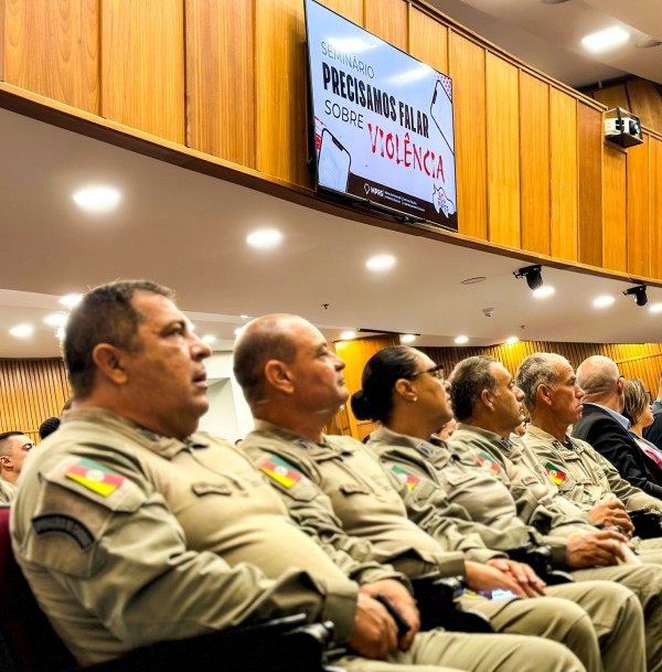 Brigadianos estão na plateia do Seminário e na parte superior da foto aparece uma tela com o titulo do evento: "Precisamos falar sobre violência extrema"