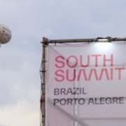 Foto mostra um letreiro com o nome South Summit Brazil Porto Alegre. Ao lado dele, um dirig&iacute;vel.