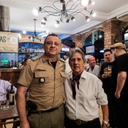 PM e artista aparecem lado a lado, no local do encontro de gaiteiros, em p&eacute; e com diversas pessoas no ambiente. 