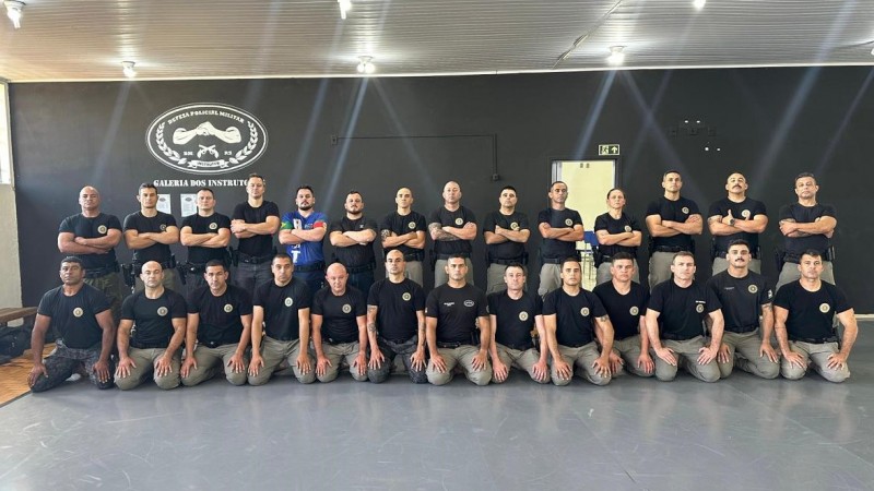 Foto mostra os instrutores que participaram do nivelamento todos reunidos em duas fileiras em cima de um tatame dentro de um gin&aacute;sio