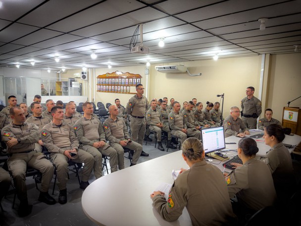 Imagem mostra um auditório com futuros capitães que olham, atentos, para a tela que mostra suas possíveis lotações