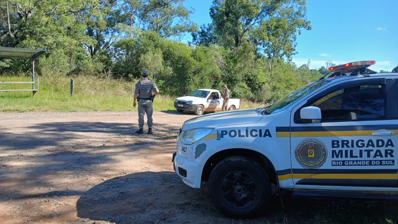 Viatura em primeiro plano ao lado da rodovia enquanto dois PMs efetuam abordagem a um ve&iacute;culo. 
