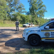 Viatura em primeiro plano ao lado da rodovia enquanto dois PMs efetuam abordagem a um ve&iacute;culo. 