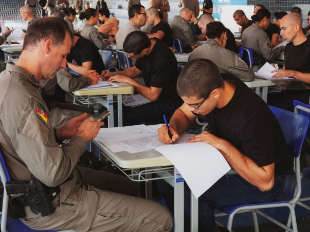 PM e aluno-soldado aparecem analisando e preenchendo documentos. 