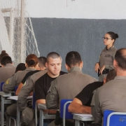 Alunos-soldados e avaliadores aparecem frente a frente nas classes dispostas no gin&aacute;sio da APM. 